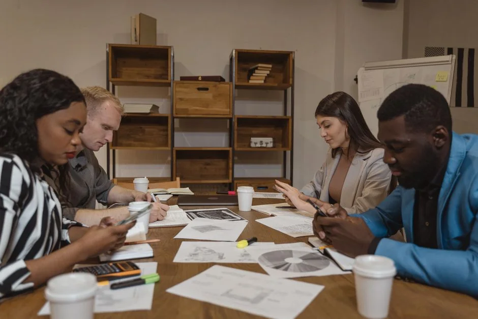 A modern workspace showing hands analyzing marketing data on a laptop and paper documents.